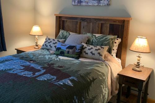 a bedroom with a bed with two lamps on tables at Whistle and Quill Lodge in Swanton