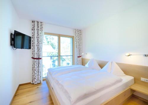 a bedroom with a white bed and a window at Landhaus Valfontana in Vandans