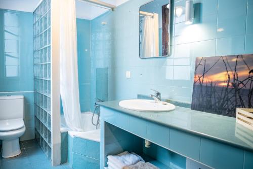 une salle de bain bleue avec un lavabo et des toilettes dans l'établissement Otra Mirada al mar, à Gijón