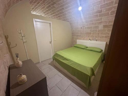- une chambre avec un lit vert et un mur en briques dans l'établissement futura home centro storico 5 minuti da Bari, à Modugno