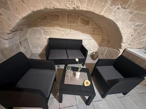 2 chaises et une table en face d'un mur en pierre dans l'établissement futura home centro storico 5 minuti da Bari, à Modugno