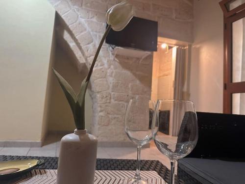 un vase avec une fleur et deux verres à vin sur une table dans l'établissement futura home centro storico 5 minuti da Bari, à Modugno