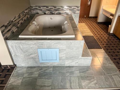 a bath tub in a bathroom with a tile floor at Sky Lodge Inn & Suites - Delavan in Delavan