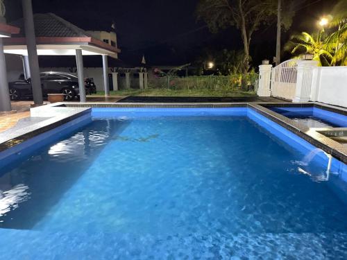 a large blue swimming pool at night at MY VILLA PD in Port Dickson
