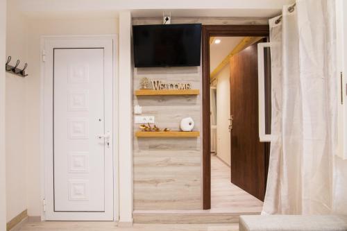 a hallway with a white door and a tv on a wall at Olimpias Nest Corfu in Corfu