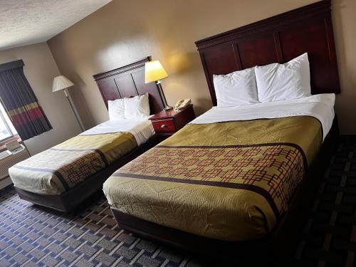 a hotel room with two beds and a lamp at Sky Lodge Inn & Suites - Delavan in Delavan