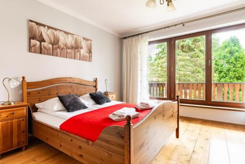 a bedroom with a wooden bed with a red blanket at Willa Marta Zakopane in Zakopane