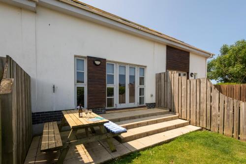a patio with a wooden table and a fence at Bay Retreat Villas in Padstow