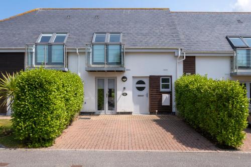 a white house with bushes in front of it at Bay Retreat Villas in Padstow