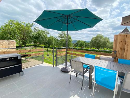 un patio avec une table et un parasol dans l'établissement Entre ciel et Lot, à Prayssac