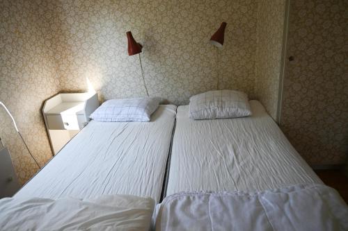 two beds in a bedroom with two lamps on the wall at Rolfskärrs Stugby in Nygård
