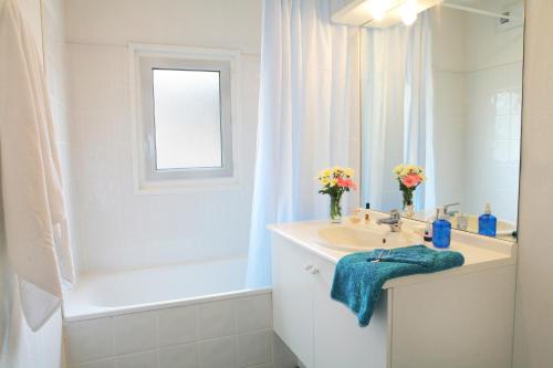 uma casa de banho branca com um lavatório e uma banheira em Résidence Néméa Les Rives de Saint Brice em Arès