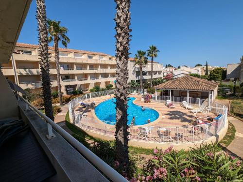 une vue sur la piscine d'un complexe hôtelier avec des palmiers dans l'établissement Sol-y-Days Mayflower, appartements climatisés résidence avec piscine proche centre, au Grau-du-Roi