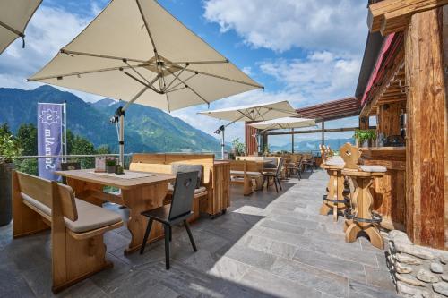 un patio con mesas, sillas y sombrillas en Alpendorf Hotel Stern, en Sankt Johann im Pongau