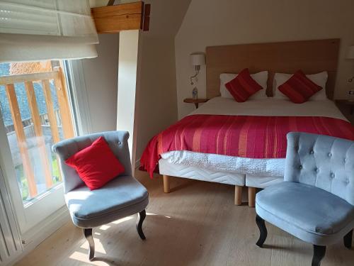 - une chambre avec un lit doté d'oreillers rouges et d'une chaise dans l'établissement Auberge du Vieux Tour Le Manoir, à Canapville