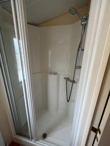 a shower with a glass door in a bathroom at Seaside Chalet in Quilty