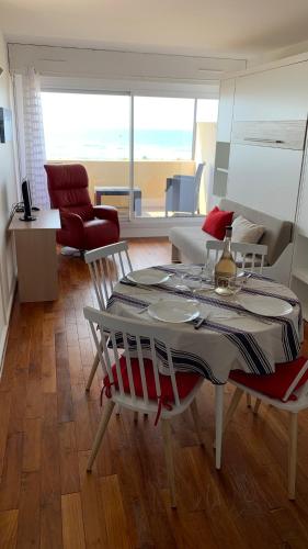 a dining table and chairs in a living room at T2 Rés Océanides vue Océan, parking privé in Lacanau-Océan