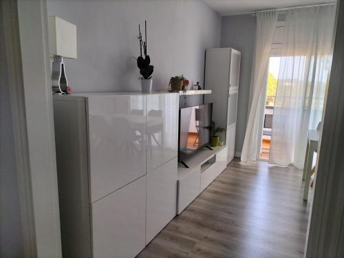 a white kitchen with a refrigerator and a wooden floor at Vilar d'Aro Apartment in S'Agaro