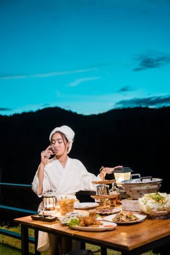 a woman sitting at a table eating food at เคียงดาว โฮมสเตย์ แก่งกระจาน in Ban Song Phi Nong