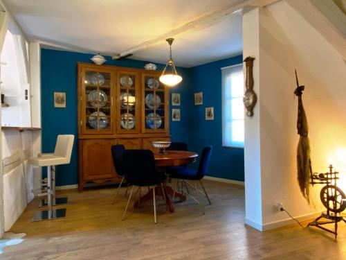 comedor con paredes azules, mesa y sillas en Laterale Residences Riquewihr, en Riquewihr