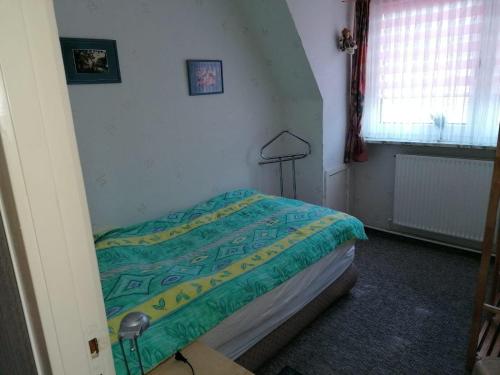 ein Schlafzimmer mit einem Bett mit einer grünen und gelben Decke in der Unterkunft westerwarft 10 in Büsum