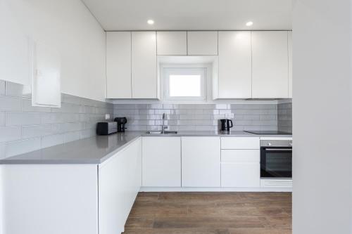 a white kitchen with white cabinets and a sink at Casa da Rocha in Baleal