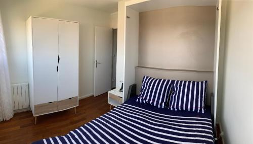 a bedroom with a blue and white striped bed and a mirror at T2 Rés Océanides vue Océan, parking privé in Lacanau-Océan
