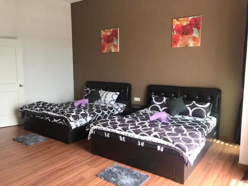 a bedroom with two beds and two pictures on the wall at Ipoh Water Front City Homestay in Ipoh