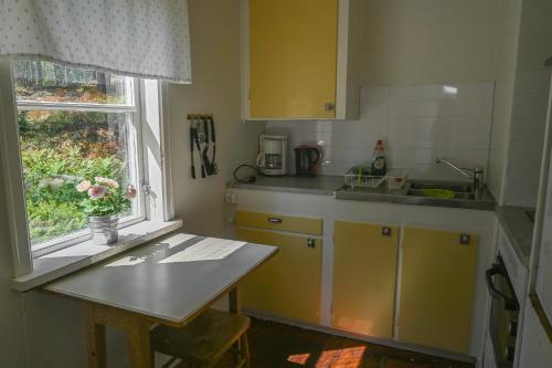 a kitchen with yellow cabinets and a table and a window at Rolfskärrs Stugby in Nygård