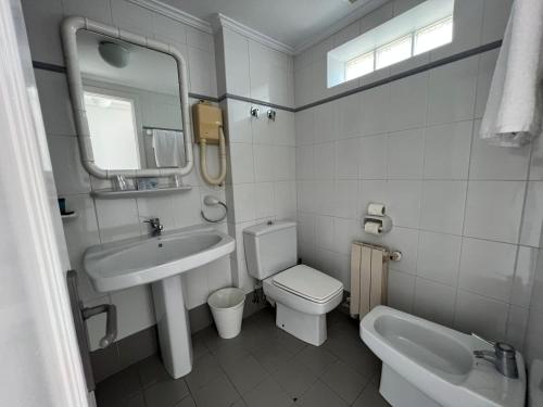 La salle de bains est pourvue d'un lavabo, de toilettes et d'un miroir. dans l'établissement Hotel Miramar Laredo, à Laredo