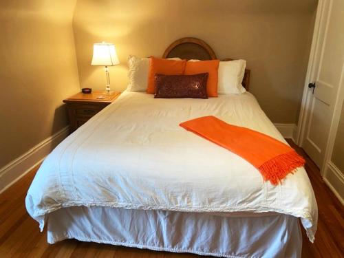 a bedroom with a bed with an orange blanket on it at Cottage on Caledonia Bed & Breakfast in Stratford