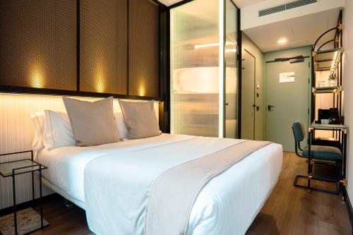 sypialnia z dużym białym łóżkiem i biurkiem w obiekcie Akeah Hotel Gran Vía w Madrycie