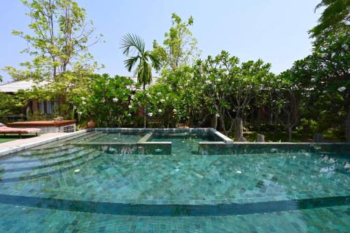 - une piscine d'eau turquoise avec des arbres dans l'établissement BaanSuk Sukhothai Resort, à Sukhothaï