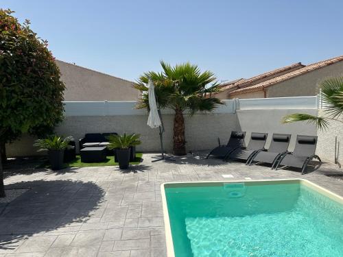 - une piscine dans une cour avec des chaises et un parasol dans l'établissement VILLA PISCINE DE LA GARRIGUE, à Florensac