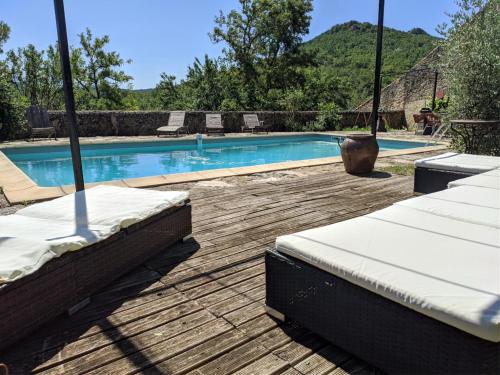 a swimming pool with two beds on a wooden deck at Gite Le Chevalier in La Répara