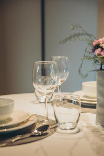 a table with three wine glasses and plates on it at Apartments Vitenberg in Cēsis
