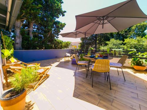 eine Terrasse mit einem Tisch, Stühlen und einem Sonnenschirm in der Unterkunft Residence ǁ Corino in Biograd na Moru