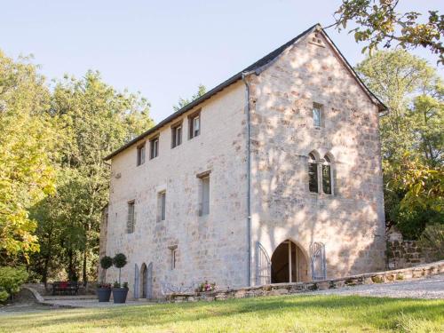 an old stone building with a grass yard at Le Moulin de la Maison des Templiers in Saint-Cernin-de-Larche