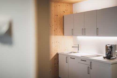 a kitchen with white cabinets and a sink at Residence Nives in Bressanone