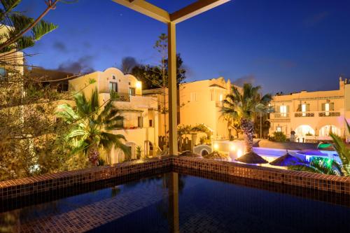 a swimming pool in front of some buildings at night at Zephyros Hotel in Kamari