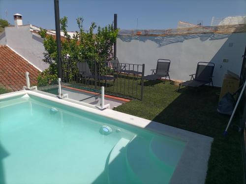 una piscina en un patio con sillas y un patio en El Barranquillo, en Cazalla de la Sierra