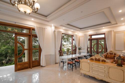 a dining room with a table and chairs and windows at Moon Valley Villas Đà Lạt in Xuan An
