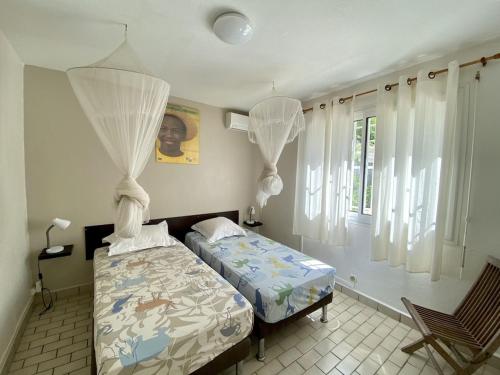 een slaapkamer met 2 aparte bedden en een raam bij Villa avec piscine privée, calme, proche des plages, à Sainte Anne in Sainte-Anne