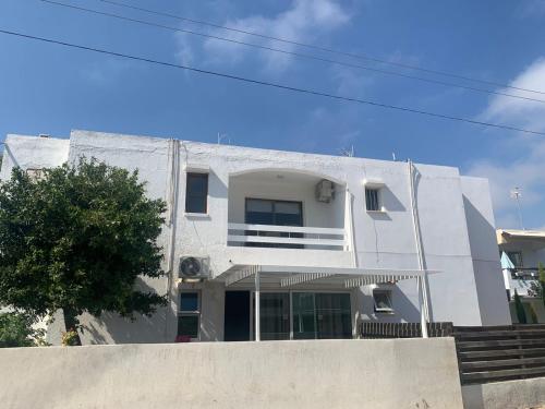 a white building with a tree in front of it at Prestige Worldwide Apartments in Ayia Napa