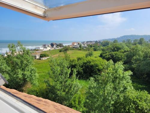 a window with a view of the ocean and trees at "Mon Évidence!" Magnifique appartement vue mer et accès direct à la plage in Villers-sur-Mer