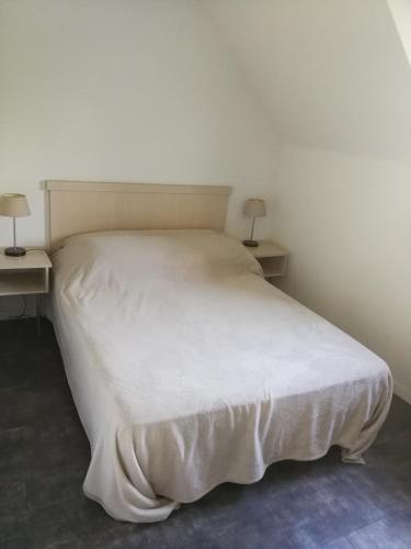 - un lit blanc dans une chambre avec deux tables dans l'établissement Domaine de l Emeraude, au Tronchet