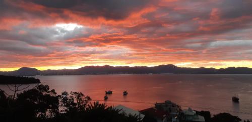 um pôr do sol sobre um grande corpo de água com barcos em Marques Home em Porto Belo