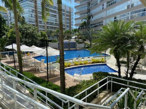 a pool with chairs and umbrellas in a resort at Piscina Aquecida-Wifi-Net-Condomínio Reserva da Mata Módulo 8 Riviera de São Lourenço in Riviera de São Lourenço