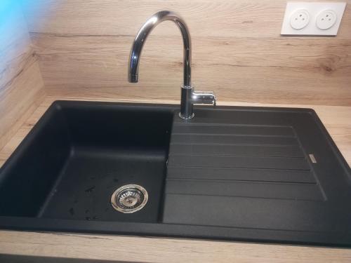 a black sink with a faucet in a kitchen at Domaine de l Emeraude in Le Tronchet
