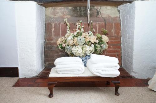 a table with towels and a bouquet of flowers at Character 2 double bedroom cottage in Shaftesbury in Shaftesbury